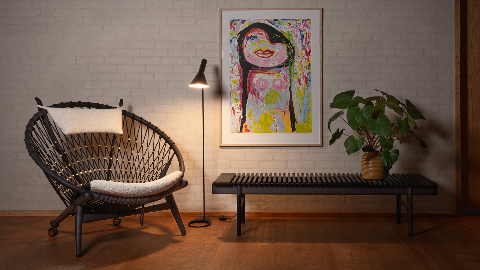 PP130 chair with white cushion in a room with a colorful painting on the wall.