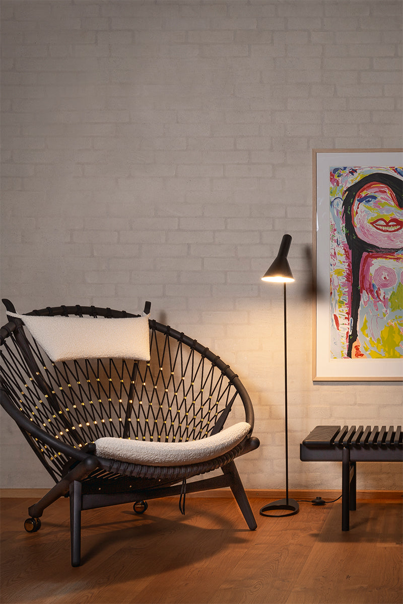 PP130 chair with white cushion in a room with a colorful painting on the wall.