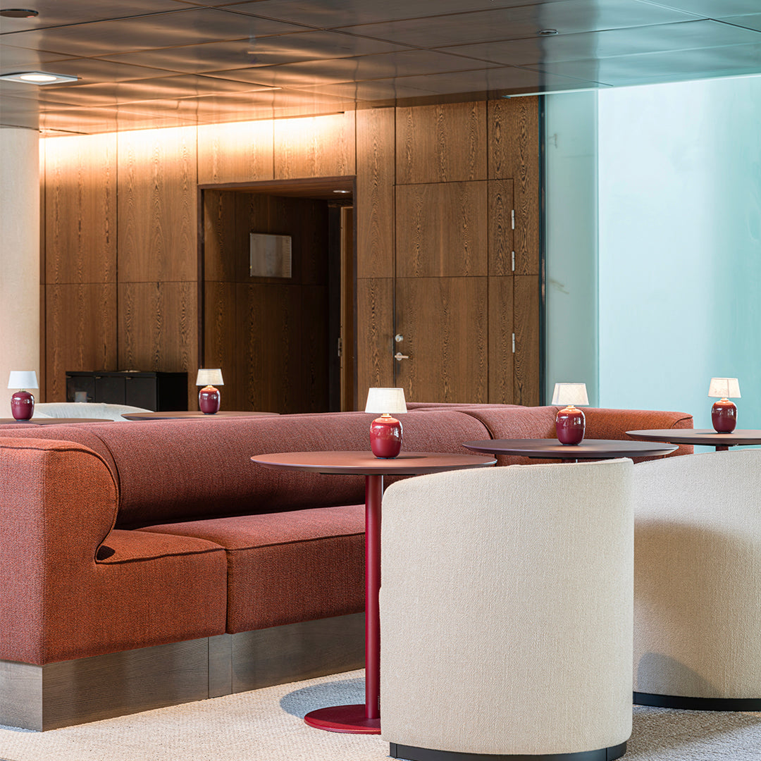 Rust-colored sofa with modern cream seating, sleek tables, and soft lighting in a stylish interior setting.