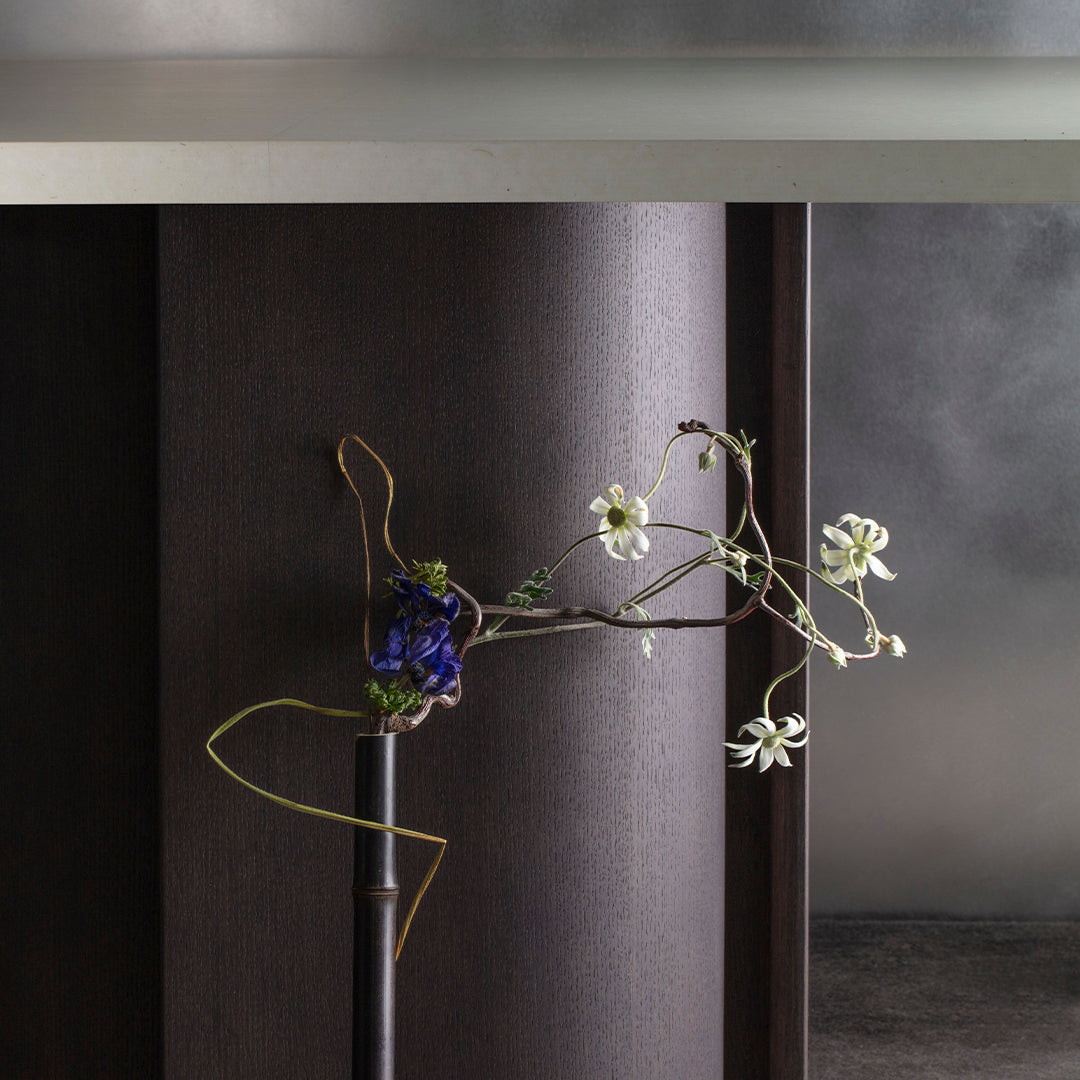 "Elegant purple and white floral arrangement with delicate green accents against a sleek dark background."