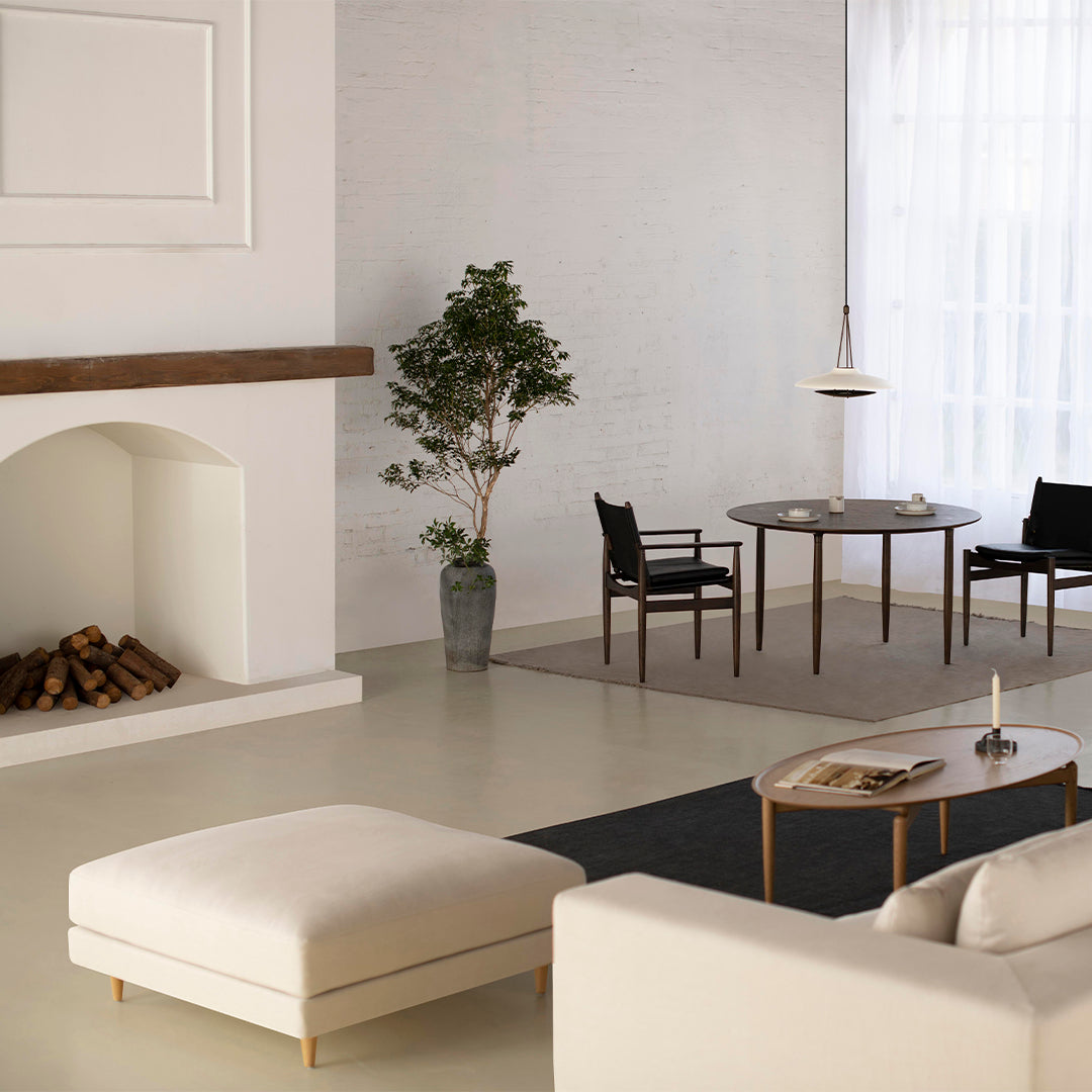 Modern living room featuring neutral tones, a soft cream ottoman, and earthy accents with geometric patterns.