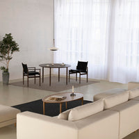 Neutral beige sofa, black dining chairs, gray table, and light curtains create a modern, minimalist living space.