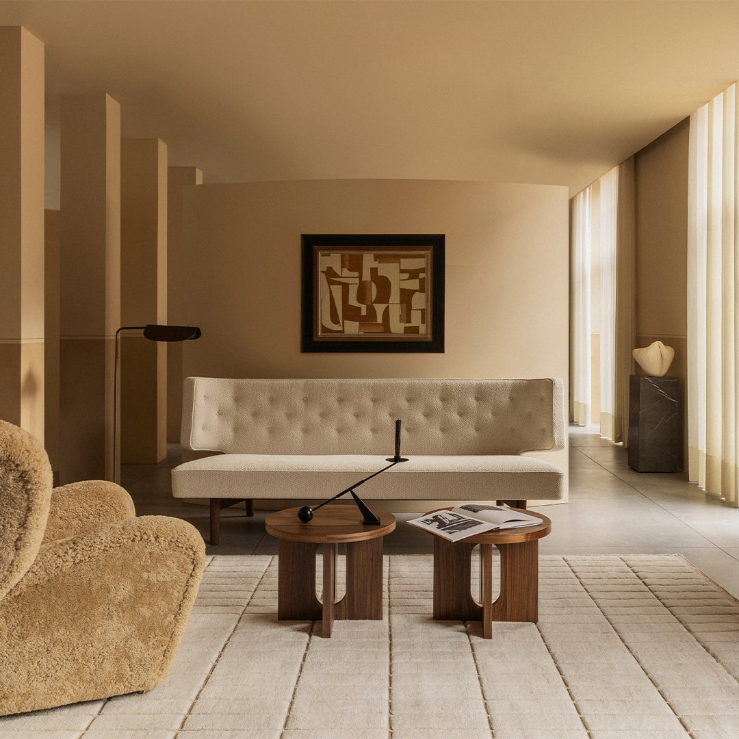 Beige sofa with tufted design, light earthy tones, and natural wood accent tables in a minimalist, elegant setting.