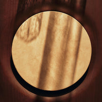 Round gold accent piece with a smooth finish, contrasted by a dark circular border, showcasing soft shadow patterns.