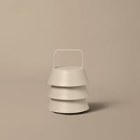 White stacked bowls with a minimalist design and a sleek handle on a neutral beige background.