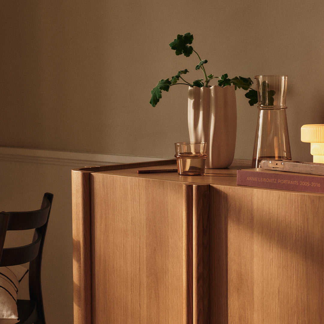 Natural wood tones with warm beige and subtle glass accents, featuring a sleek minimalist design and decorative plants.