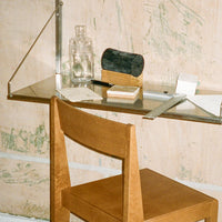 Natural wood chair with a minimalist, warm tone; stainless steel shelf featuring clear glass and textured black accents.
