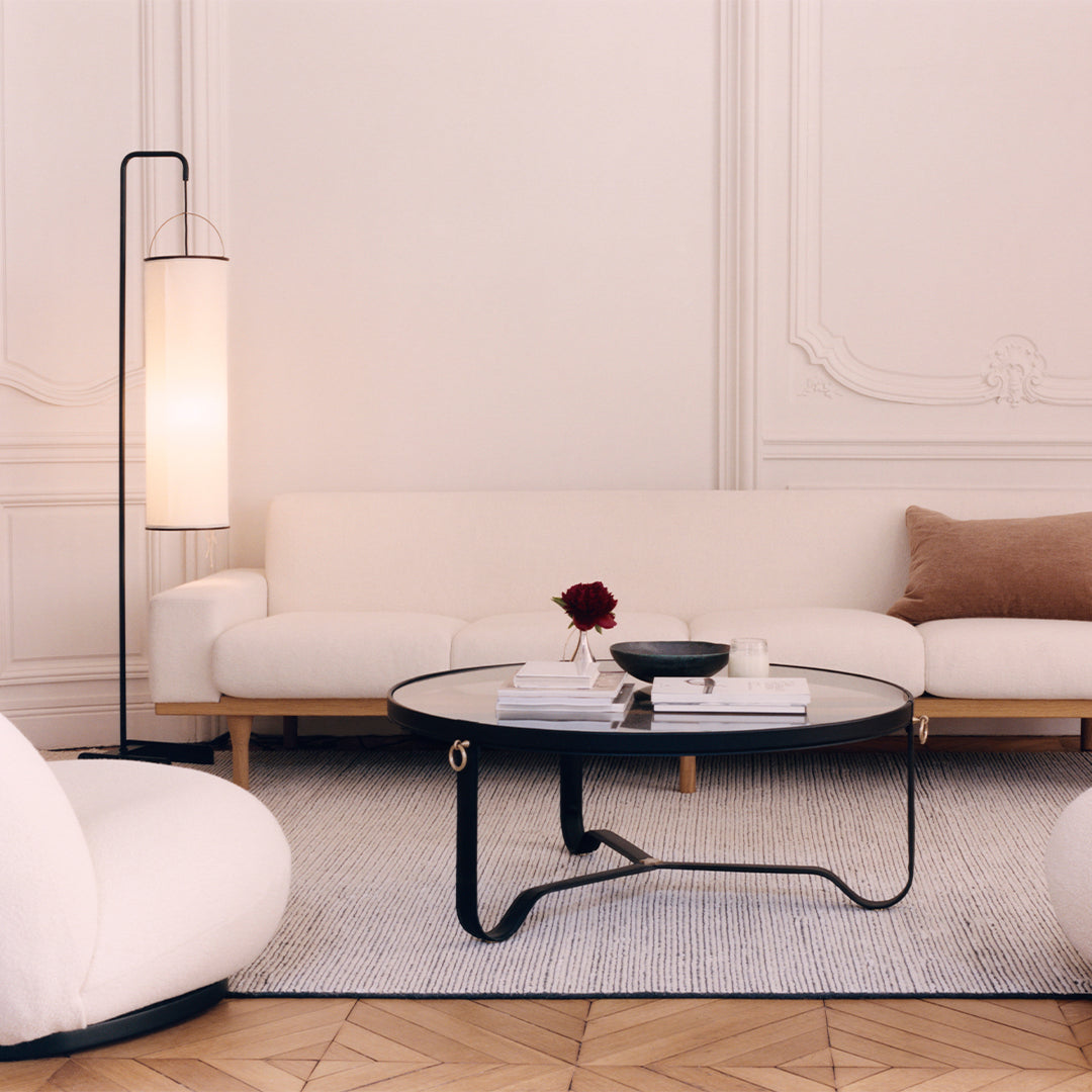 Minimalist living room featuring a white sofa, black coffee table, and beige accents on a light-toned wood floor.
