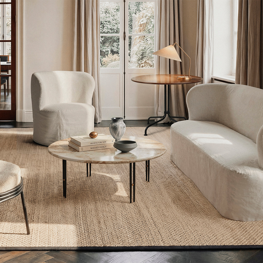 Modern living room with neutral beige and cream furniture, featuring smooth textures and a natural woven rug.