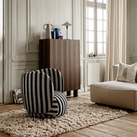 Black and white striped chair on a plush rug, set against a light-toned wood floor and neutral walls.