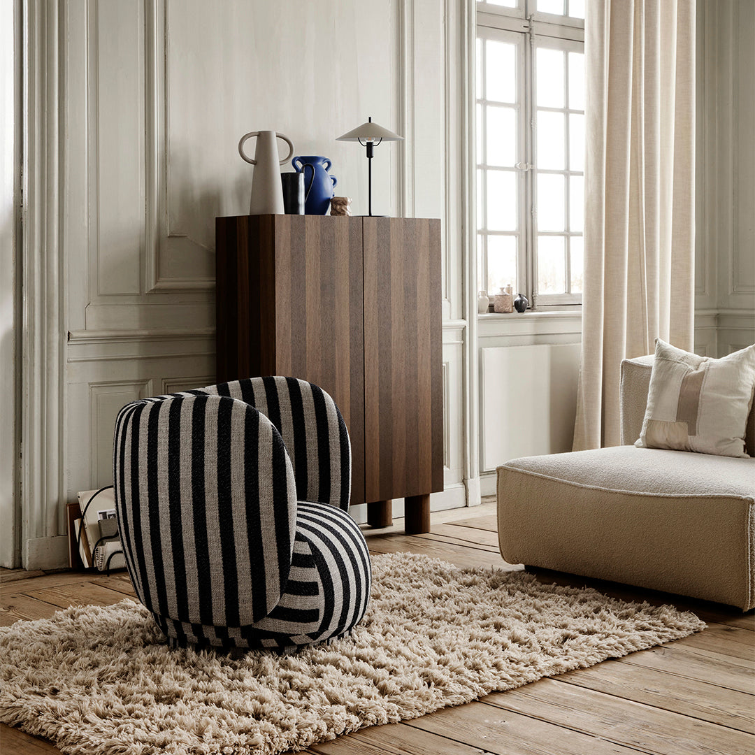 "Black and white striped accent chair in a stylish room with wood tones and neutral textures."