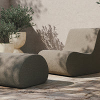 Soft beige lounge chair and ottoman with smooth, curved shapes, set against a neutral, textured background.