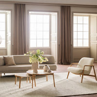 Light beige sofa with soft cream accents, natural wood furniture, and pastel floral arrangement in a minimalistic space.