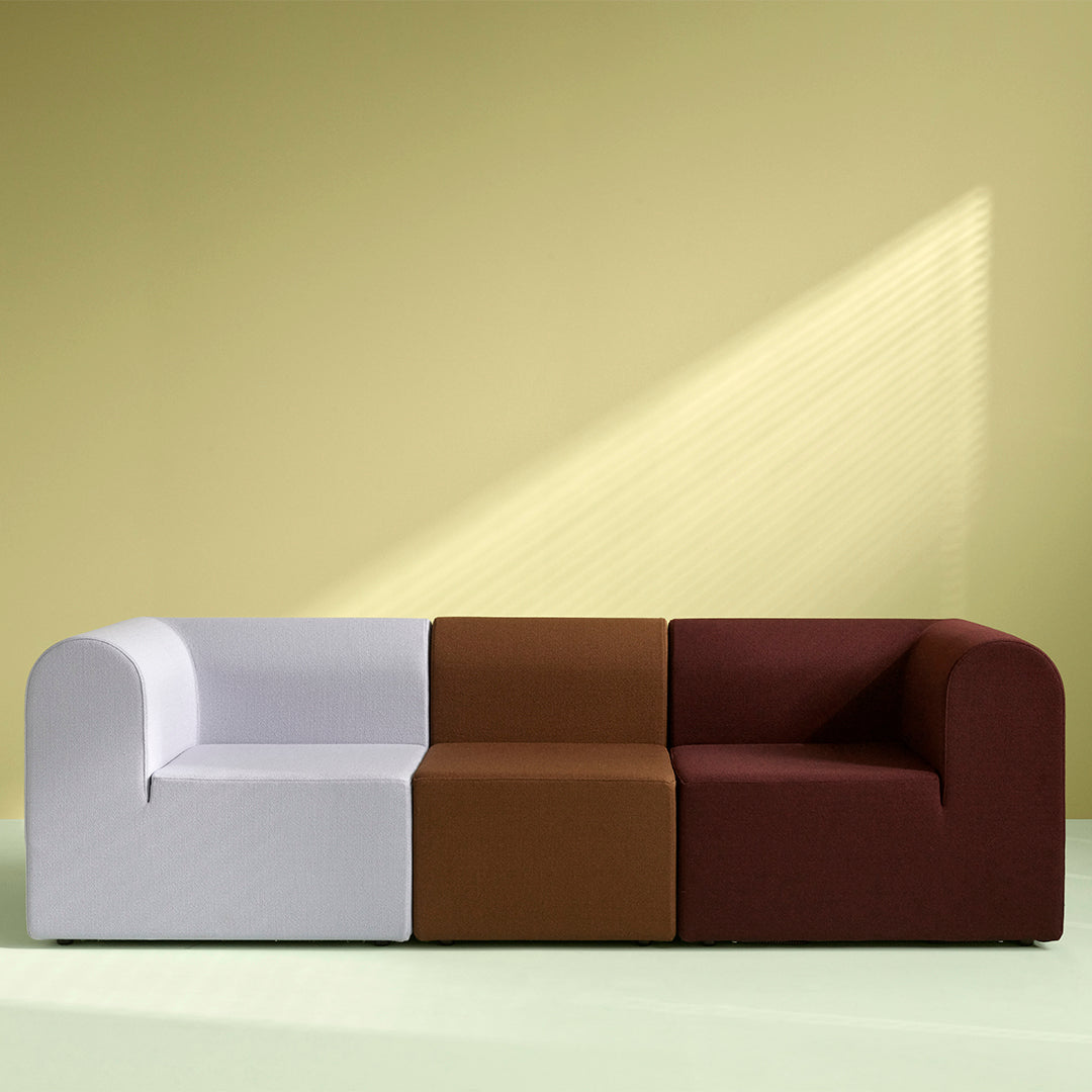 Multicolored sofa featuring white, brown, and burgundy blocks against a soft green and yellow backdrop.