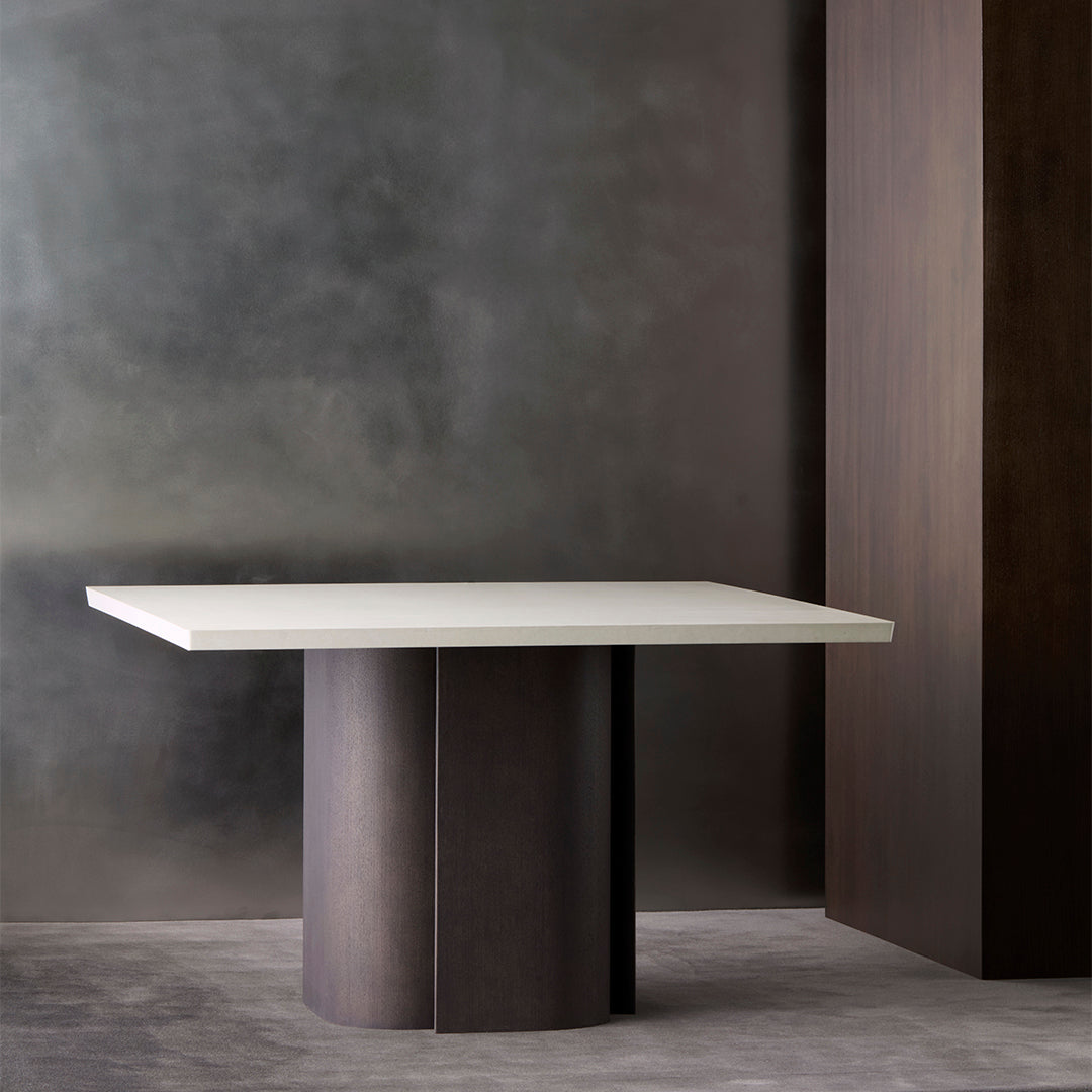 Modern white countertop table with dark wood cylindrical base, set against a textured gray background.