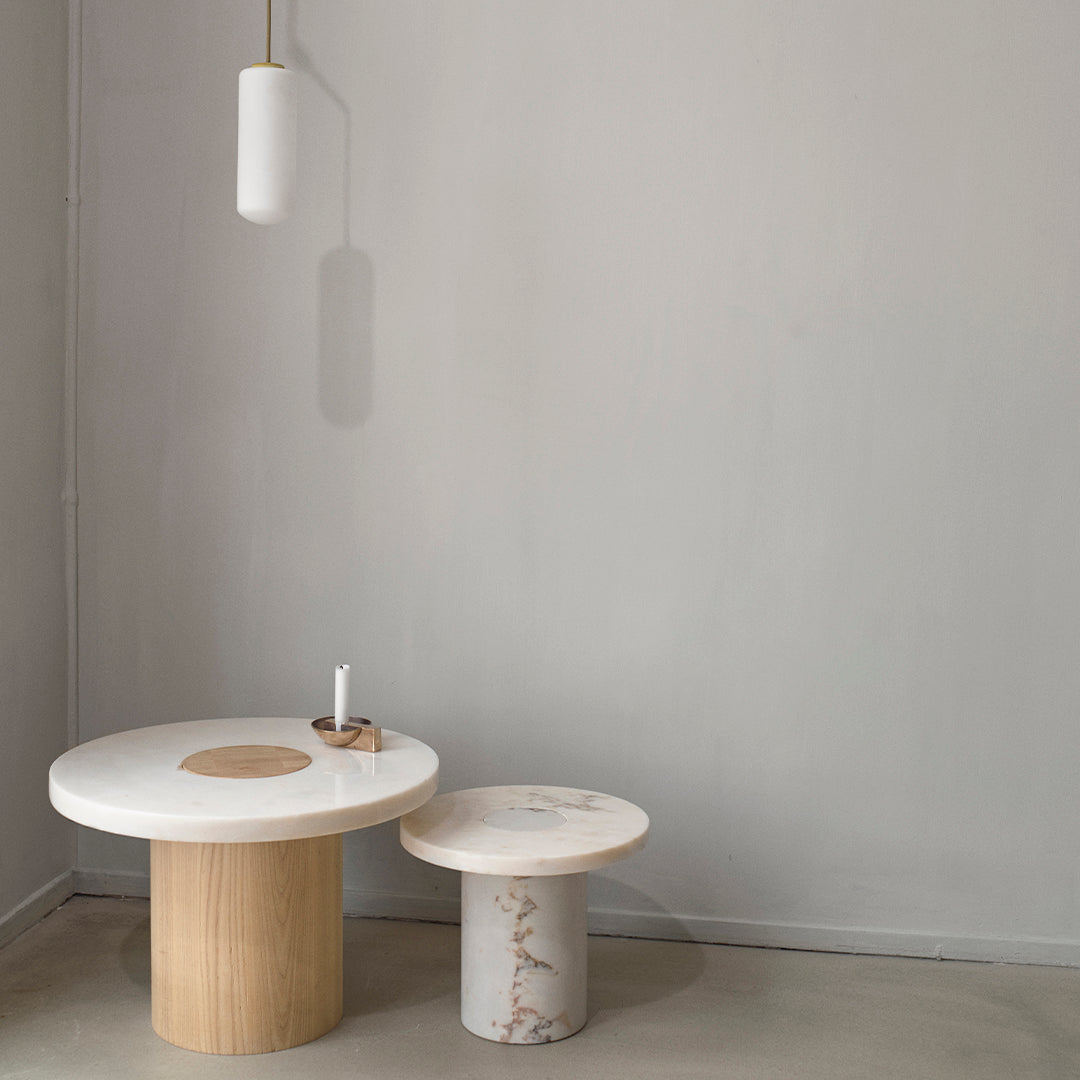 White and beige circular tables with wood and marble patterns against a minimalistic gray background. Simple, modern design.