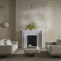 Light gray sofas with a textured pattern, beige walls, and a soft brown rug create a calm, modern living space.