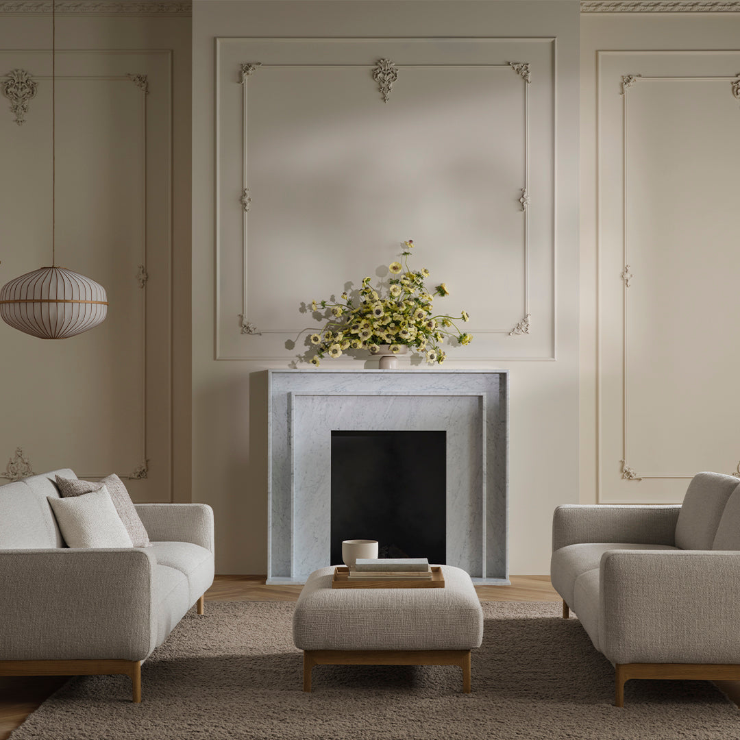 "Neutral beige sofas with textured fabric against a soft gray fireplace in a minimalist, elegant living room setting."