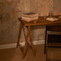 Wooden desk with a rich brown finish, surrounded by textured pale pink and muted gray wall, featuring a woven beige rug.