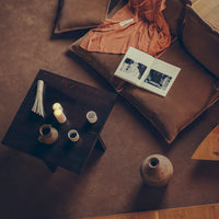 Warm earthy tones with soft textures, featuring rich brown, terracotta, and subtle patterns on pillows and table decor.