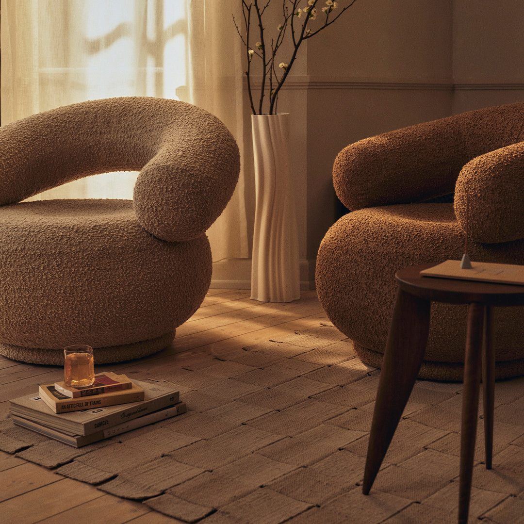 "Cozy beige and brown lounge chairs with soft, curved shapes in a warm-toned living room setting."