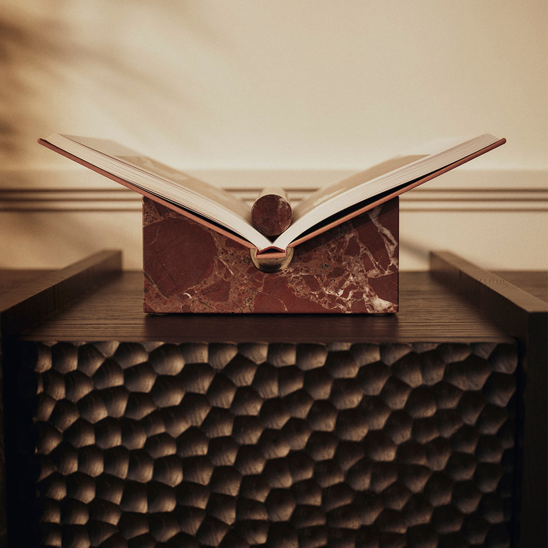 "Open book on a marbled burgundy box, featuring elegant, rich tones and dynamic patterns."
