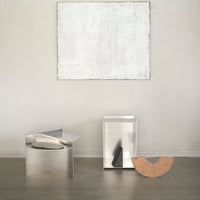 Silver metallic furniture with sleek, modern shapes, complemented by a neutral beige and white accent wall.