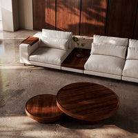 "Modern white sofa with plush cushions and dark wood round coffee tables in a stylish, minimalistic interior."
