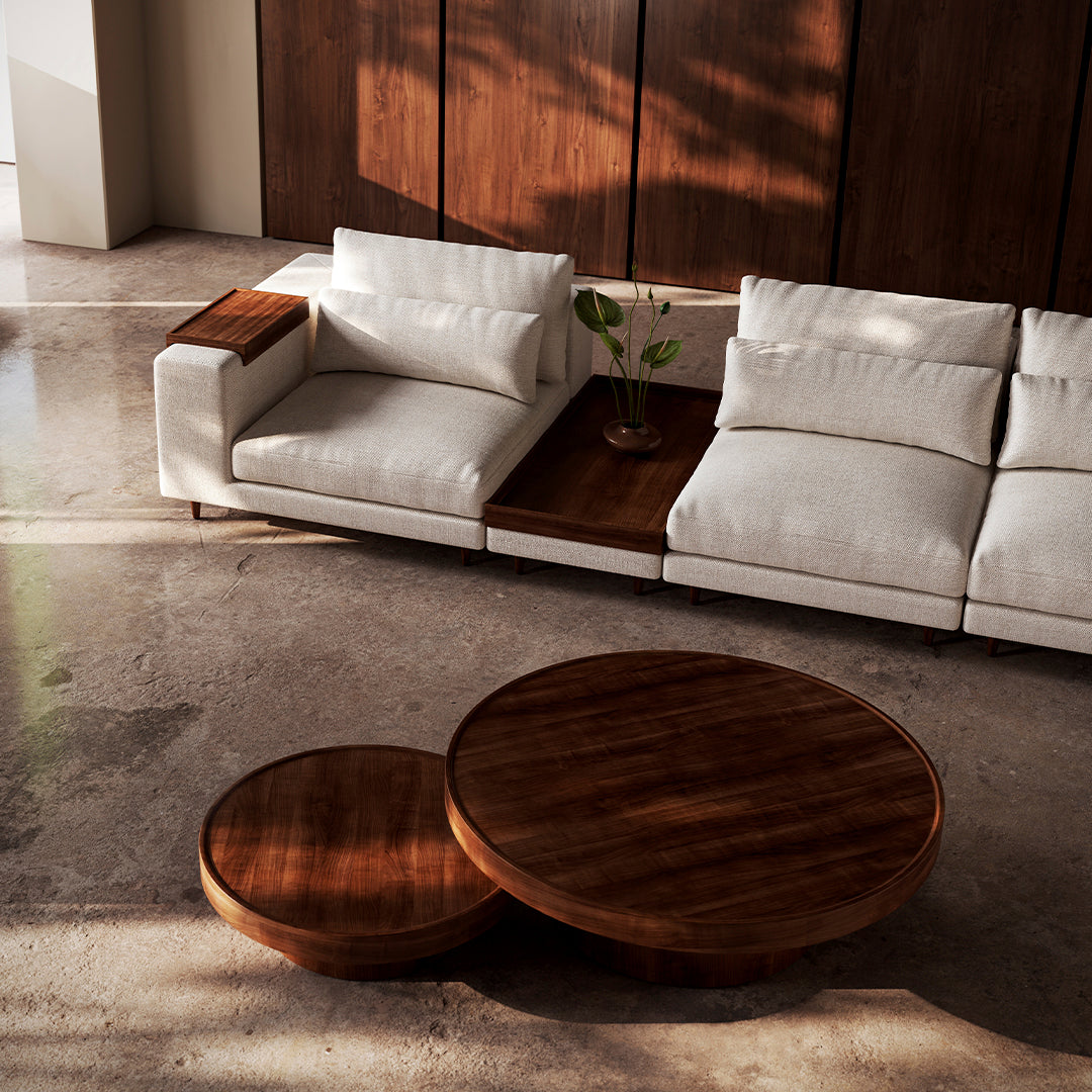 Elegant white sofa with wood accents, paired with round wooden coffee tables in a modern, minimalist setting.