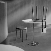 Stylish black and white minimalistic furniture featuring a round table, stools, and sleek, modern lines.
