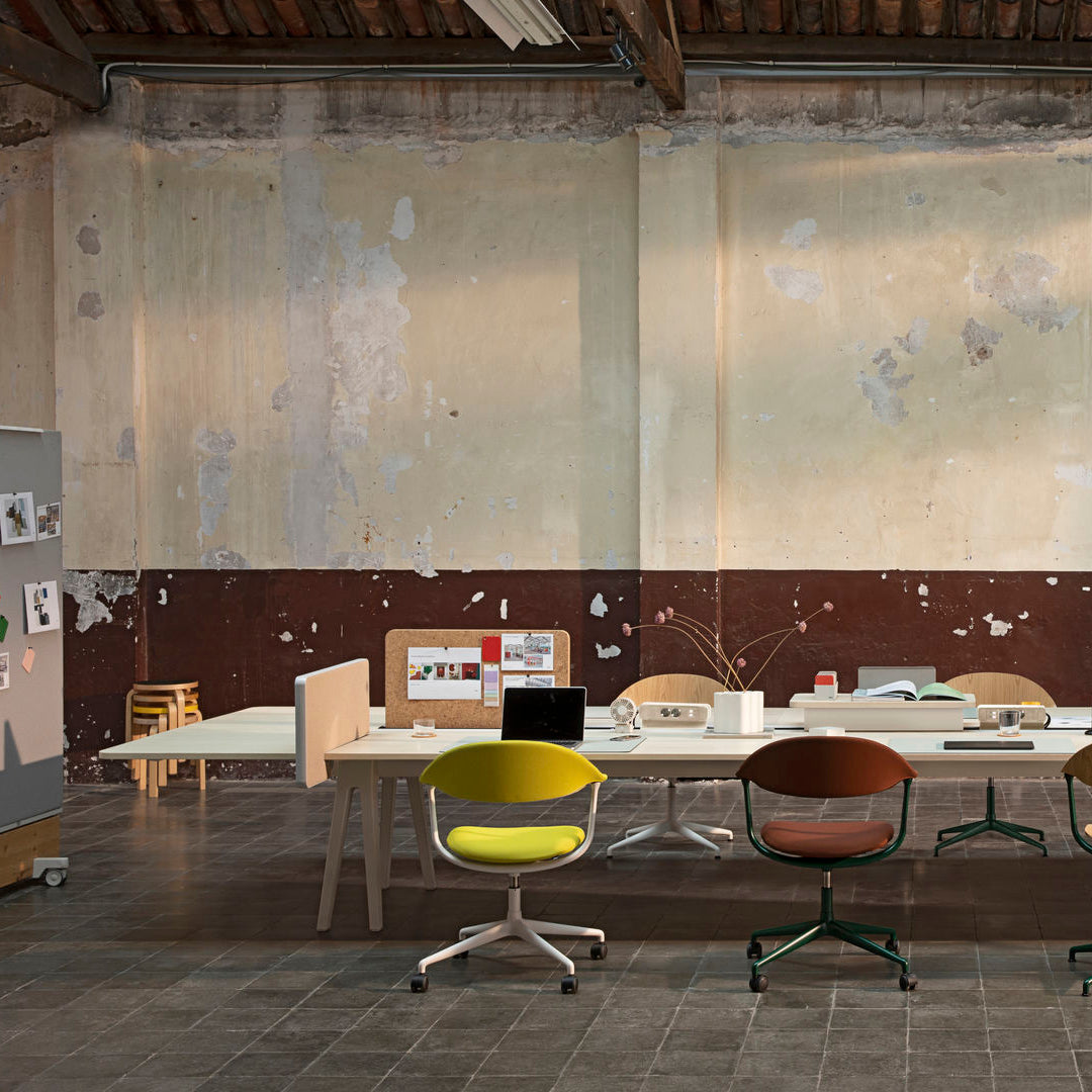 Colorful office chairs in yellow, brown, and green set against a textured beige and maroon wall. Modern design elements.