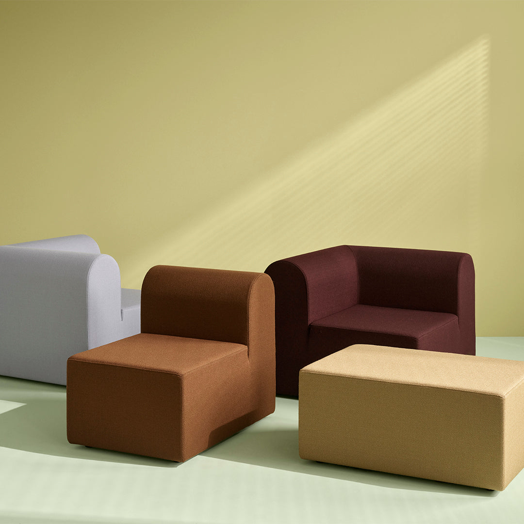 Colorful modern furniture in muted tones: light gray, rich brown, deep burgundy, and soft beige against a pastel green backdrop.