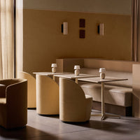 "Minimalist seating area in warm beige tones with curved chairs, simple tables, and soft textures."
