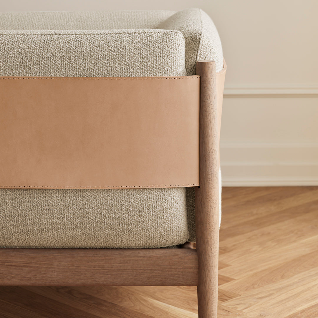 "Textured light gray cushion with smooth tan leather accent, set against warm wooden floor."