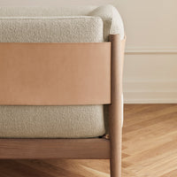 "Textured light gray cushion with smooth tan leather accent, set against warm wooden floor."