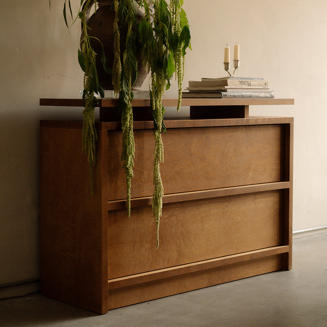 Brown wooden dresser with a smooth finish and clean lines, featuring three horizontal drawers and a stylish top.