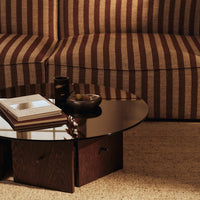 Striped brown and tan patterned upholstery with a sleek, round black glass coffee table and dark wooden base.