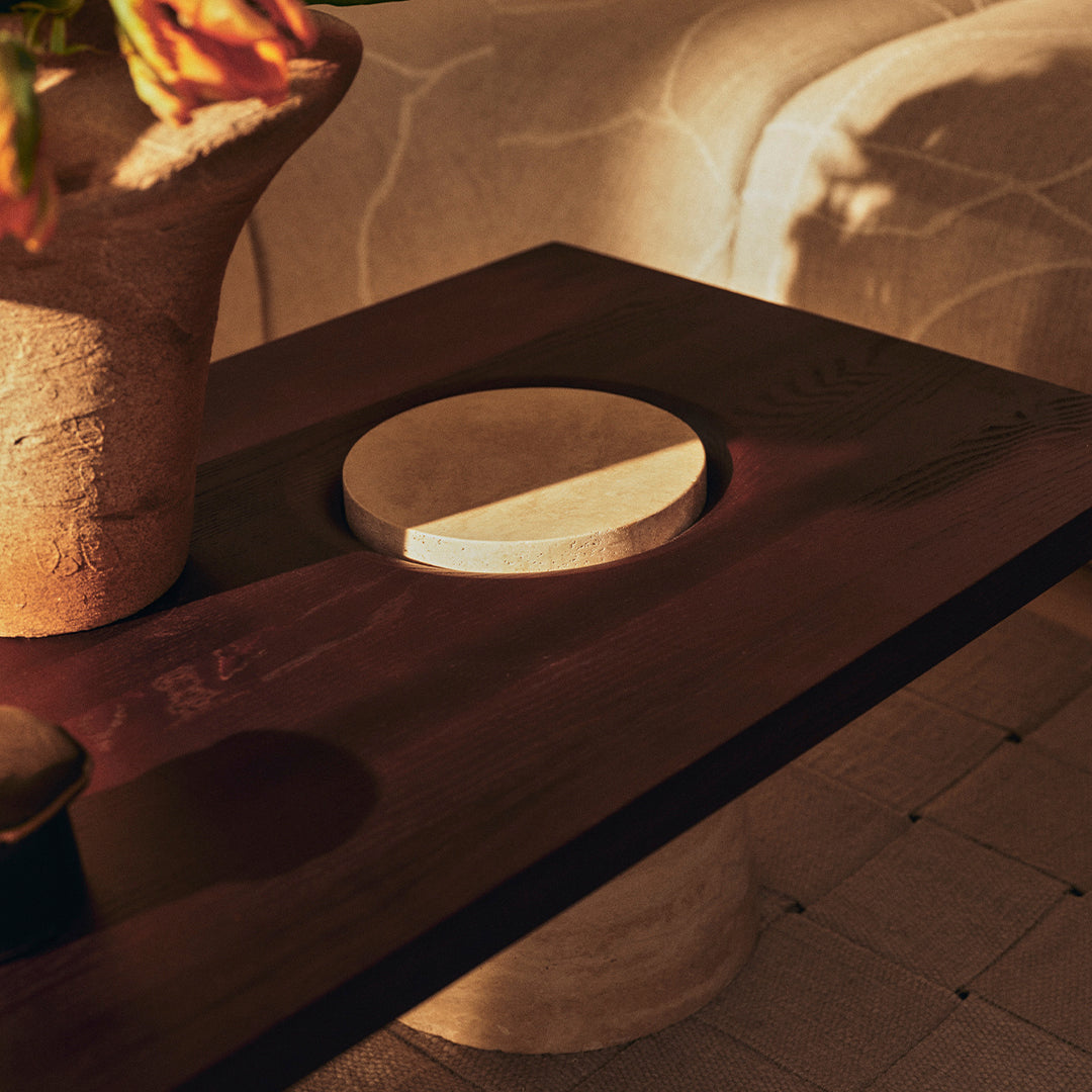 Dark wooden table with a circular stone detail, featuring soft neutral tones and subtle textures.