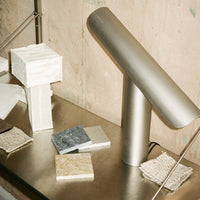 Stylish lamp on a metal surface with geometric patterns in beige, gray, and textured neutral tones.