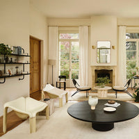 "Minimalist living room featuring neutral tones, black accents, and light wood, with modern furniture and soft textures."