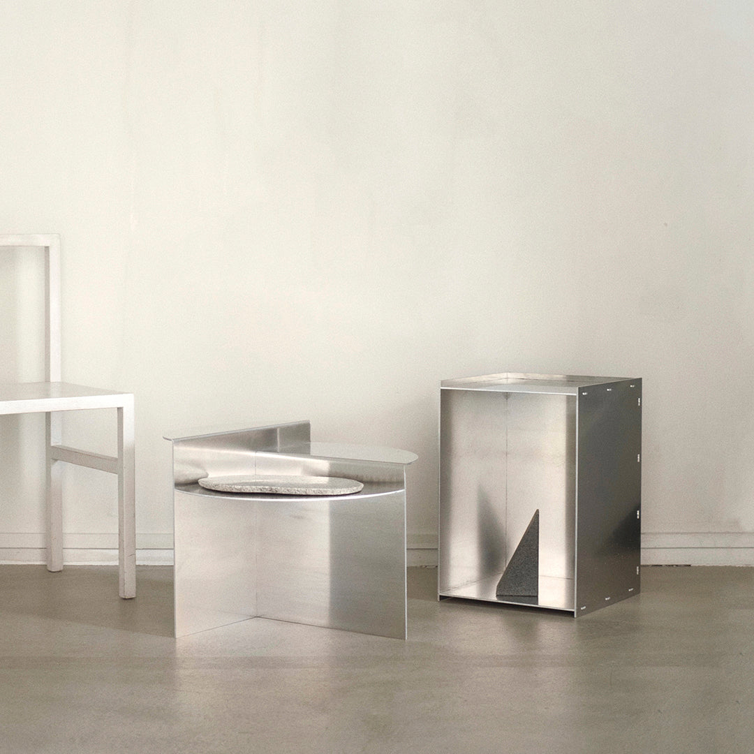Sleek metallic silver furniture with geometric patterns and clean, modern lines in a minimalist setting.