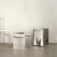 Sleek metallic silver furniture with geometric patterns and clean, modern lines in a minimalist setting.