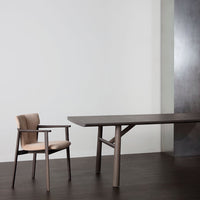 Elegant brown wooden table with a beige upholstered chair, set against a minimalist backdrop. Modern design, sleek lines.