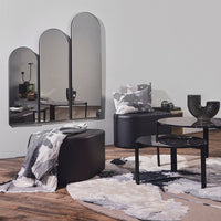 Black and gray furniture with abstract patterns, featuring a soft beige rug and mirrored accents in a modern setting.
