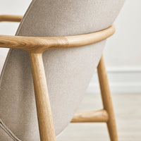 Light beige upholstered chair with a smooth, minimalist design and natural wooden frame. Perfect for modern decor.