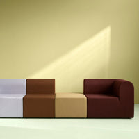 Colorful modular sofa in purple, brown, and beige against a soft yellow background. Modern geometric design.