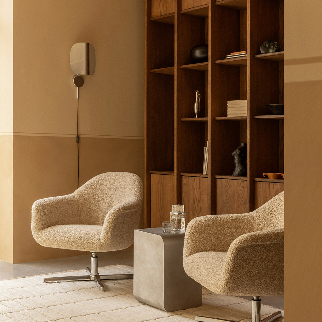 Beige textured armchairs paired with a gray concrete table in a warm, minimalist room with wood accents.
