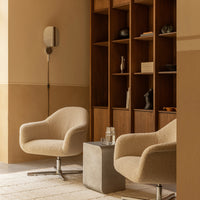Beige textured armchairs paired with a gray concrete table in a warm, minimalist room with wood accents.