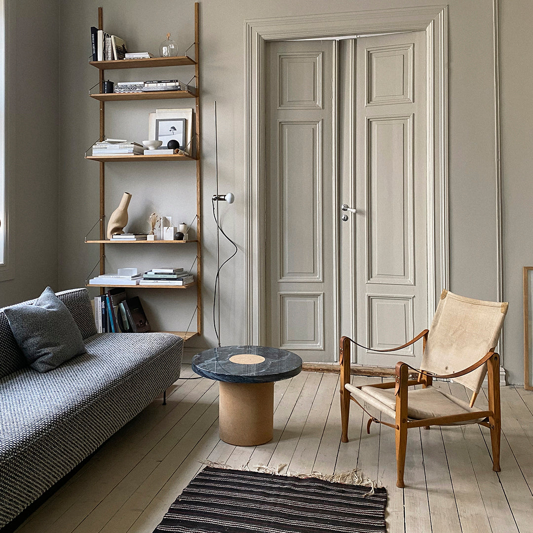 Modern living room featuring a gray-striped sofa, wooden chair, black marble table, and neutral tones with textured patterns.
