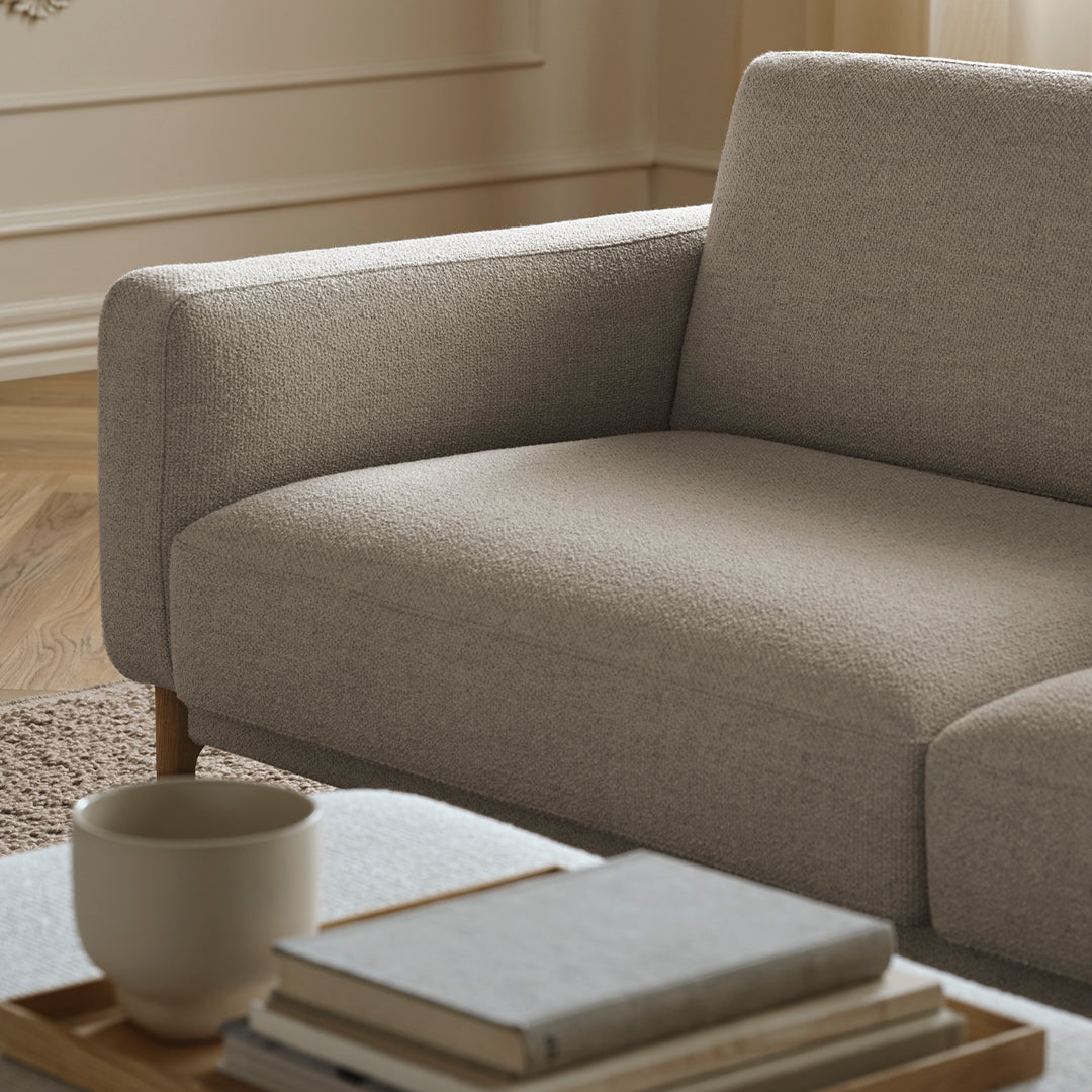 Light grey textured sofa with a minimalist design, complemented by a beige coffee table and neutral decor.